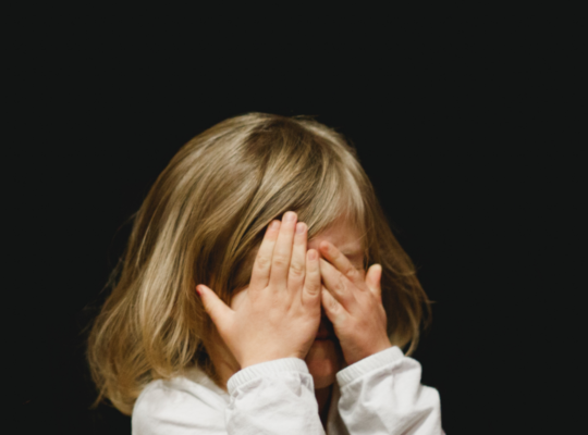 what triggers childhood ocd blog: picture of child with blonde hair covering her face with her hands